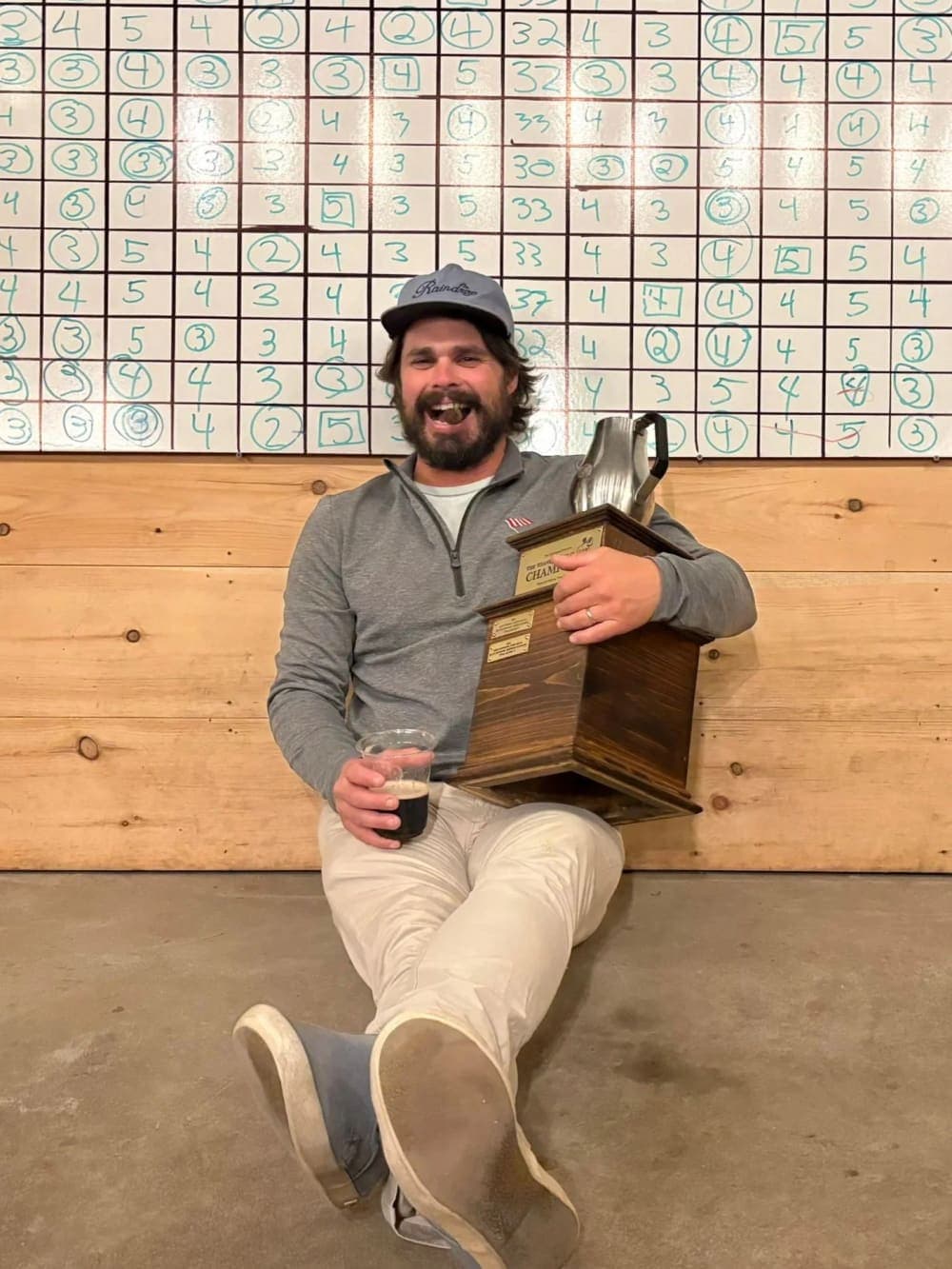 The captain on the floor with the Cup, a cigar, and a beer, in front of the scoreboard